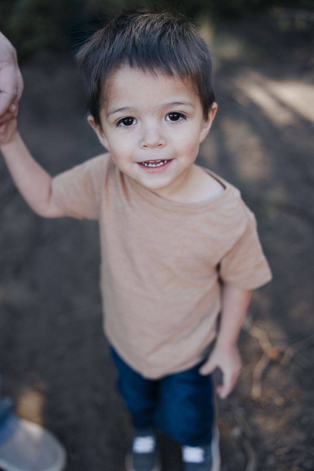 Close-up portrait of young child in tan shirt with sweet smile.