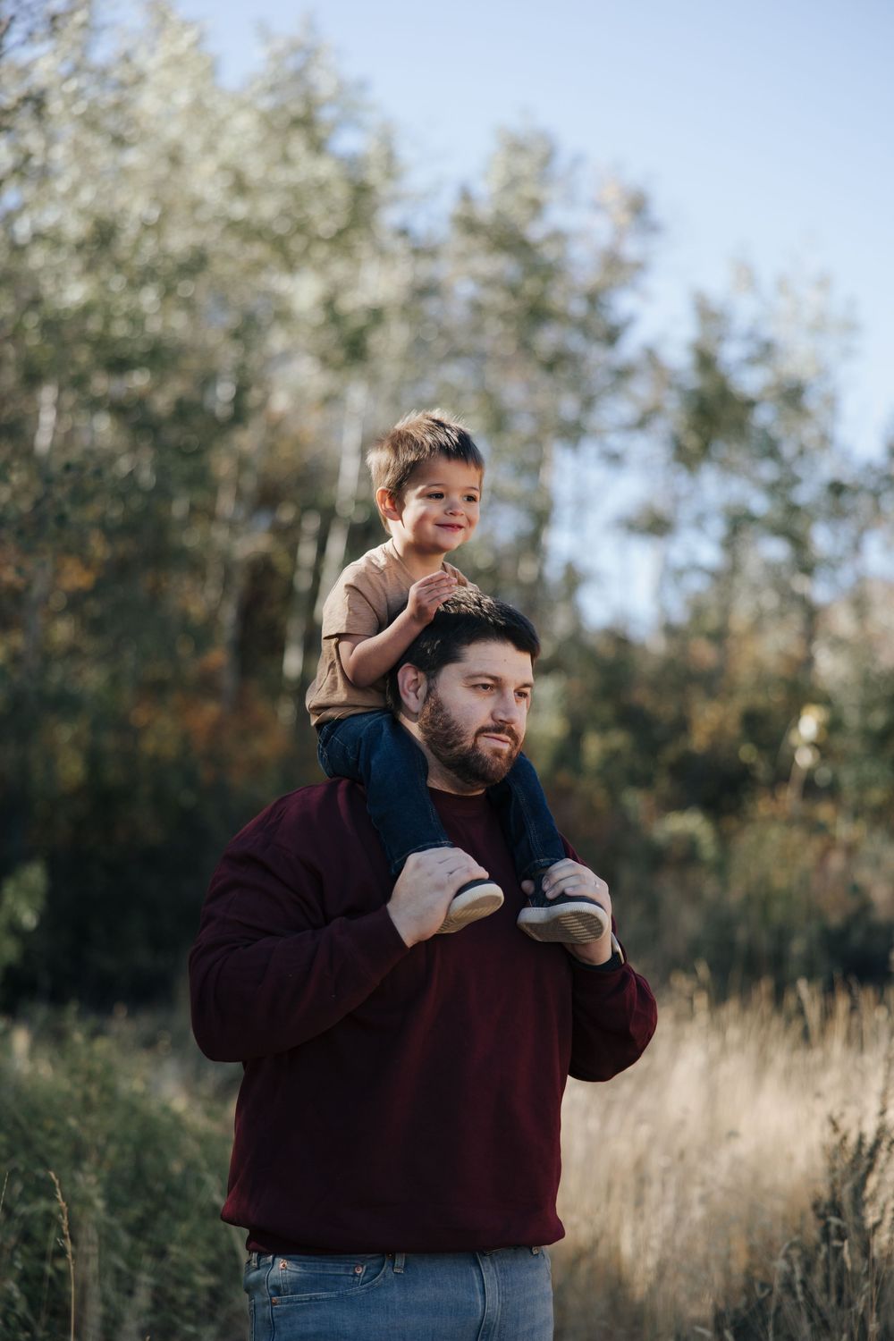 A playful outdoor photoshoot with a couple in a wooded setting with tall grass.