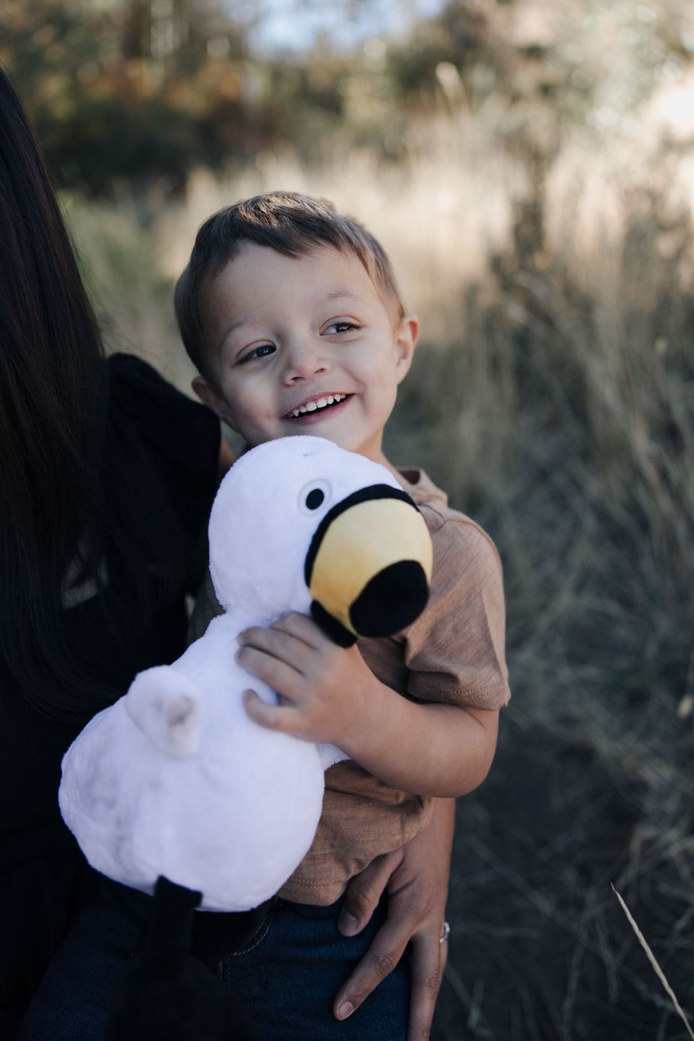 A child hugs and plays with a large white plush duck toy outdoors.