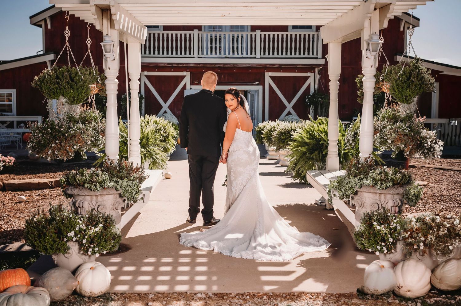 Bride and groom standing under a white gazebo at a rustic red barn wedding venue. Bessie's Barn