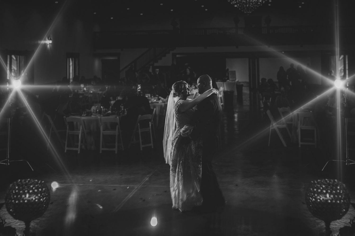 Bride and groom share romantic first dance in black and white photo with dramatic star burst lights.