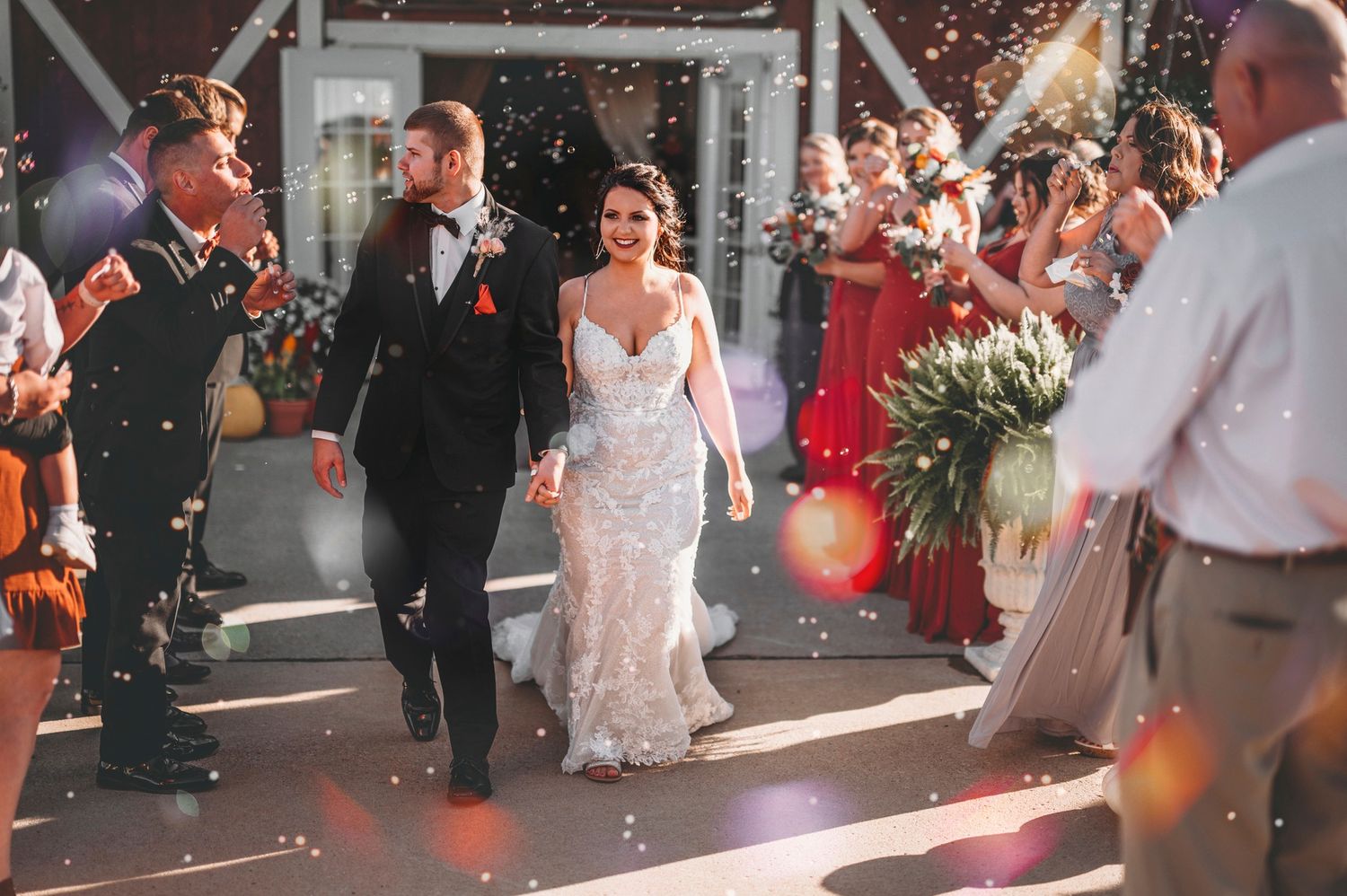 Bride and groom walking through a confetti shower surrounded by cheering wedding guests. Bessie's Barn