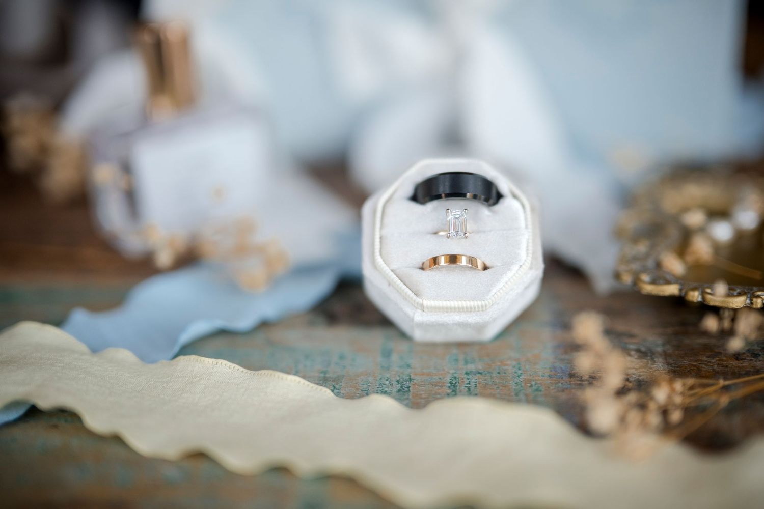 Gold wedding rings displayed in white velvet ring box on decorative table setting.