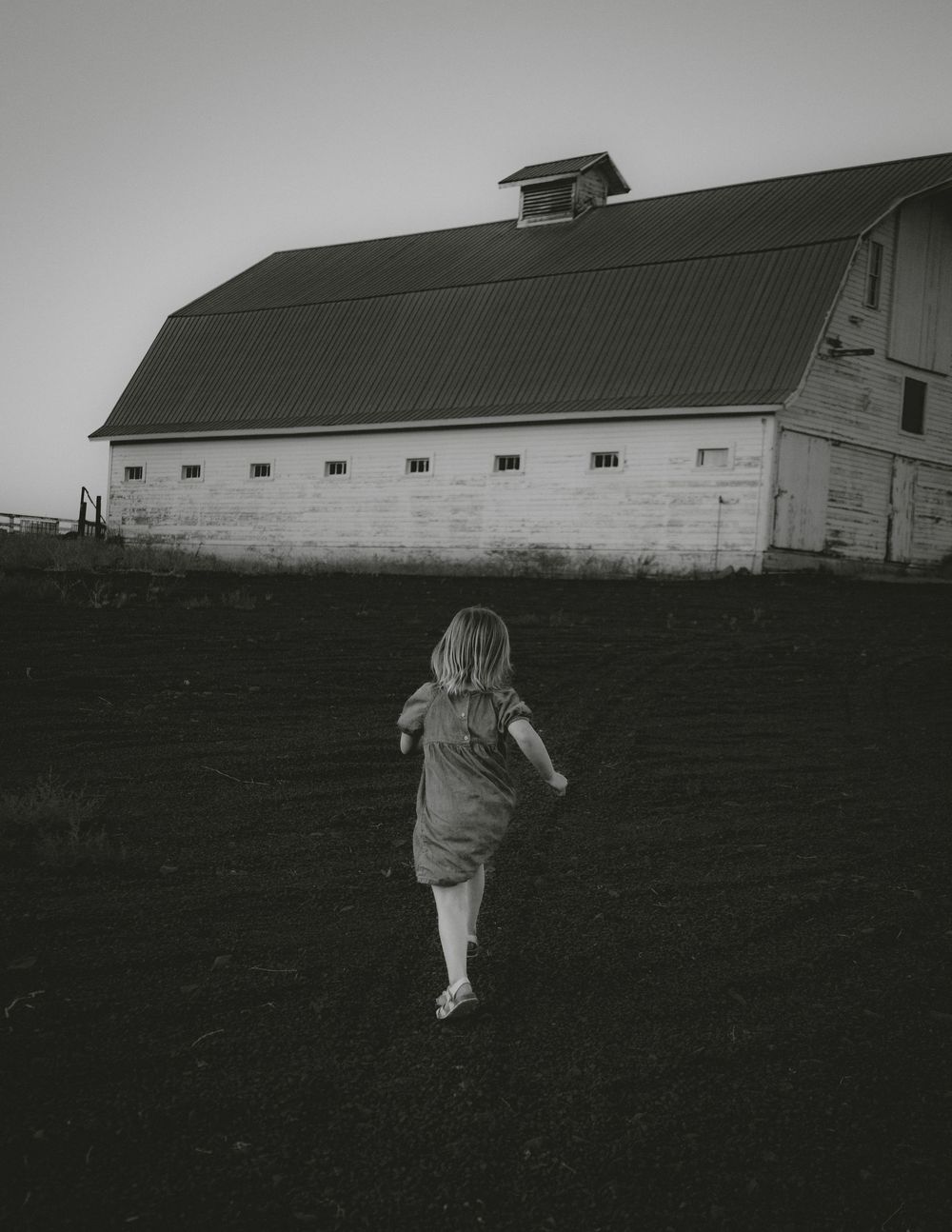 Black and white photo of a barn with silhouettes running in the foreground.