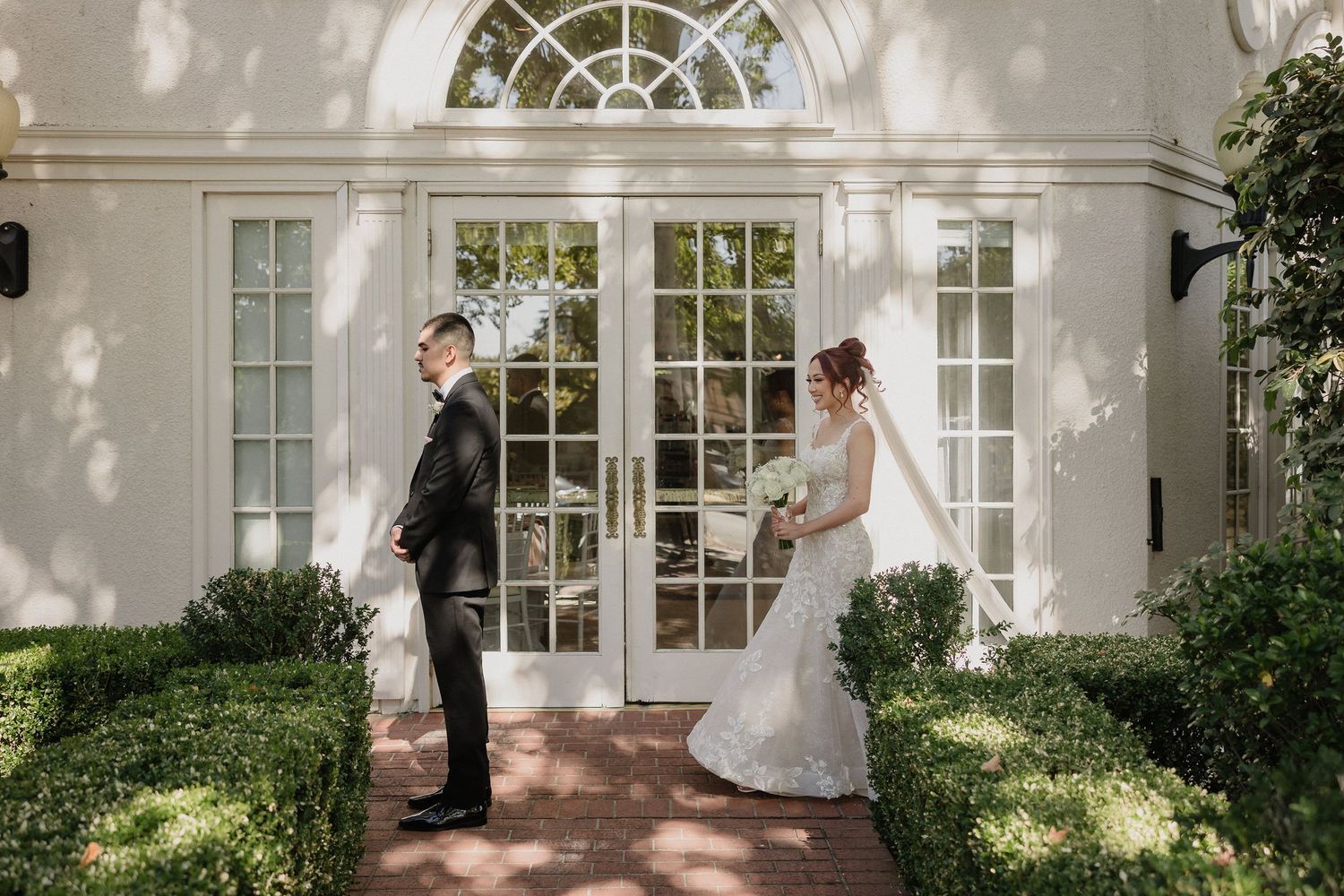 Wedding couple's first look takes place in front of elegant white colonial building with arched windows for Sacramento wedding
