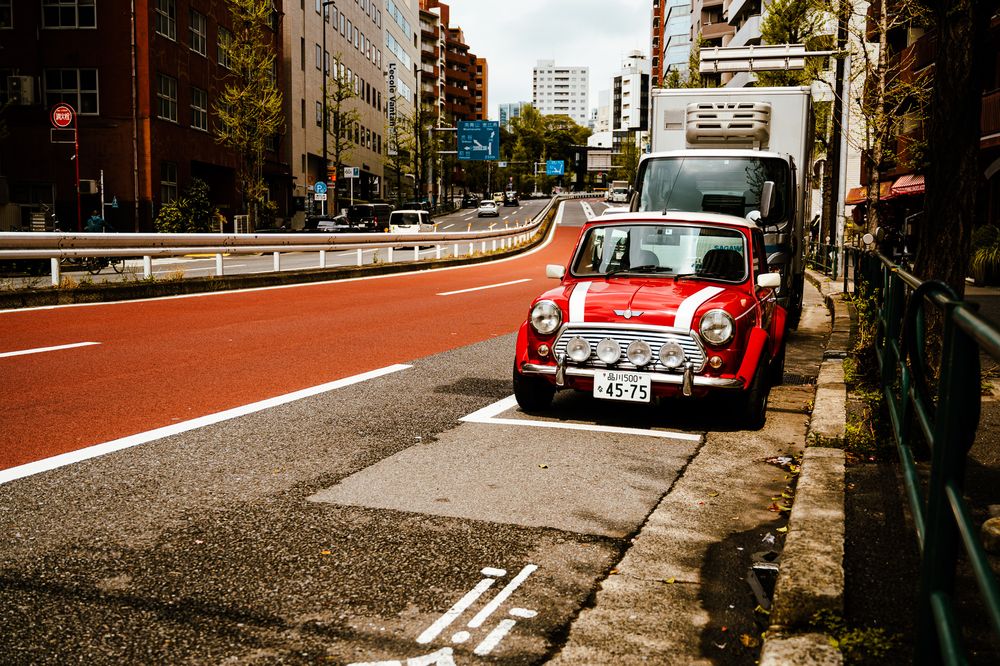 Red and white classic Volkswagen Beetles parked on a city street with buildings in the background.