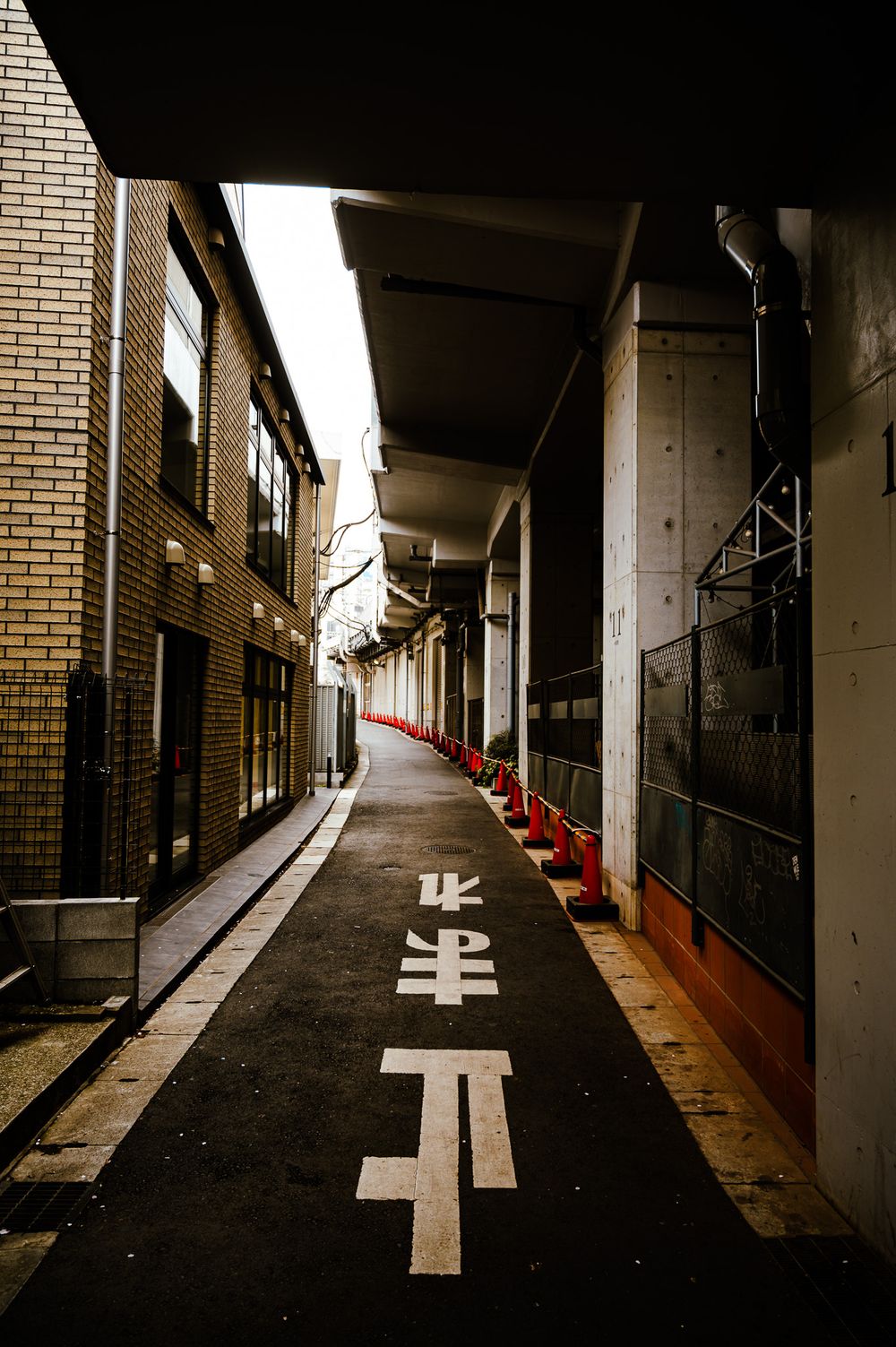 Dark corridor in a building with brick walls and directional arrows painted on the floor.