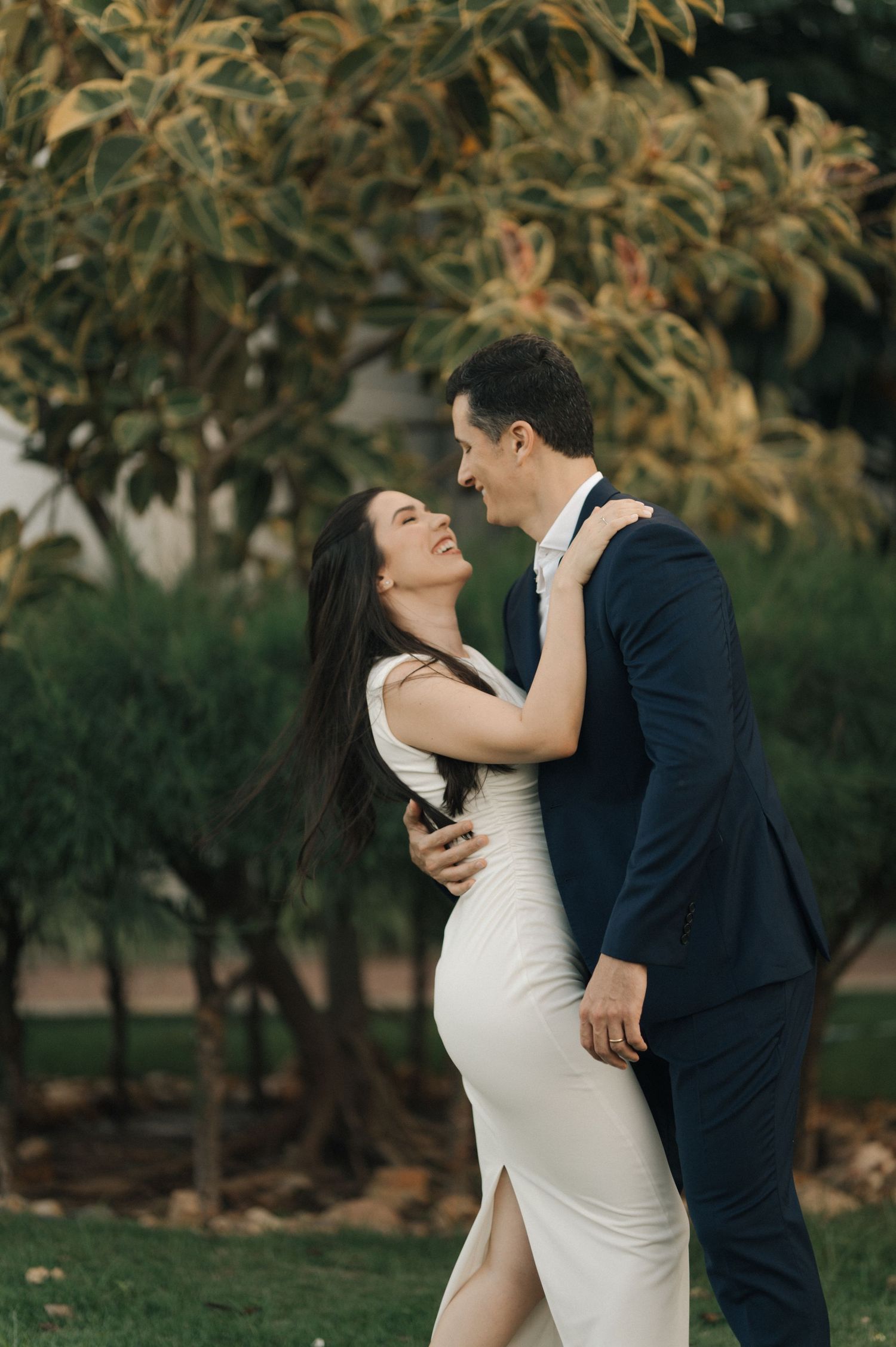 A couple shares an intimate moment in formal attire by autumn foliage.