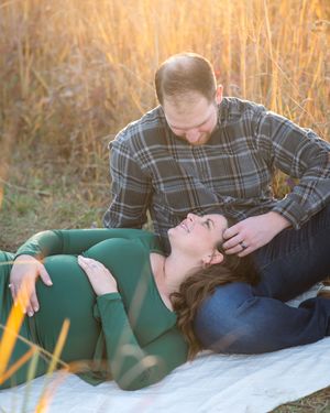 A romantic couple lounging in a canoe during golden hour in autumn while wearing casual outdoor attire.