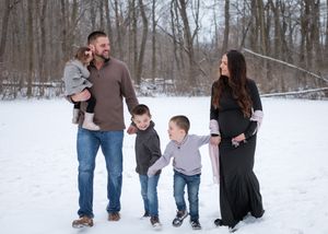 Family playing together in winter wonderland with fresh snow covering open field.