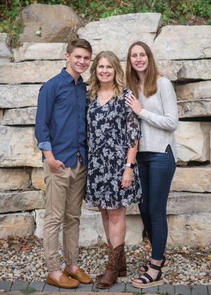 Group poses casually in front of a gray stone retaining wall on a fall afternoon.