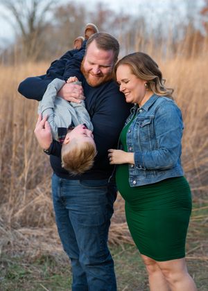 Couple sharing tender moments in tall grass during autumn photoshoot session in casual matching outfits.