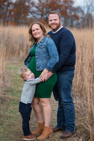 Family portrait series in a fall field with tall grass, jeans and boots showing intimate candid moments together.