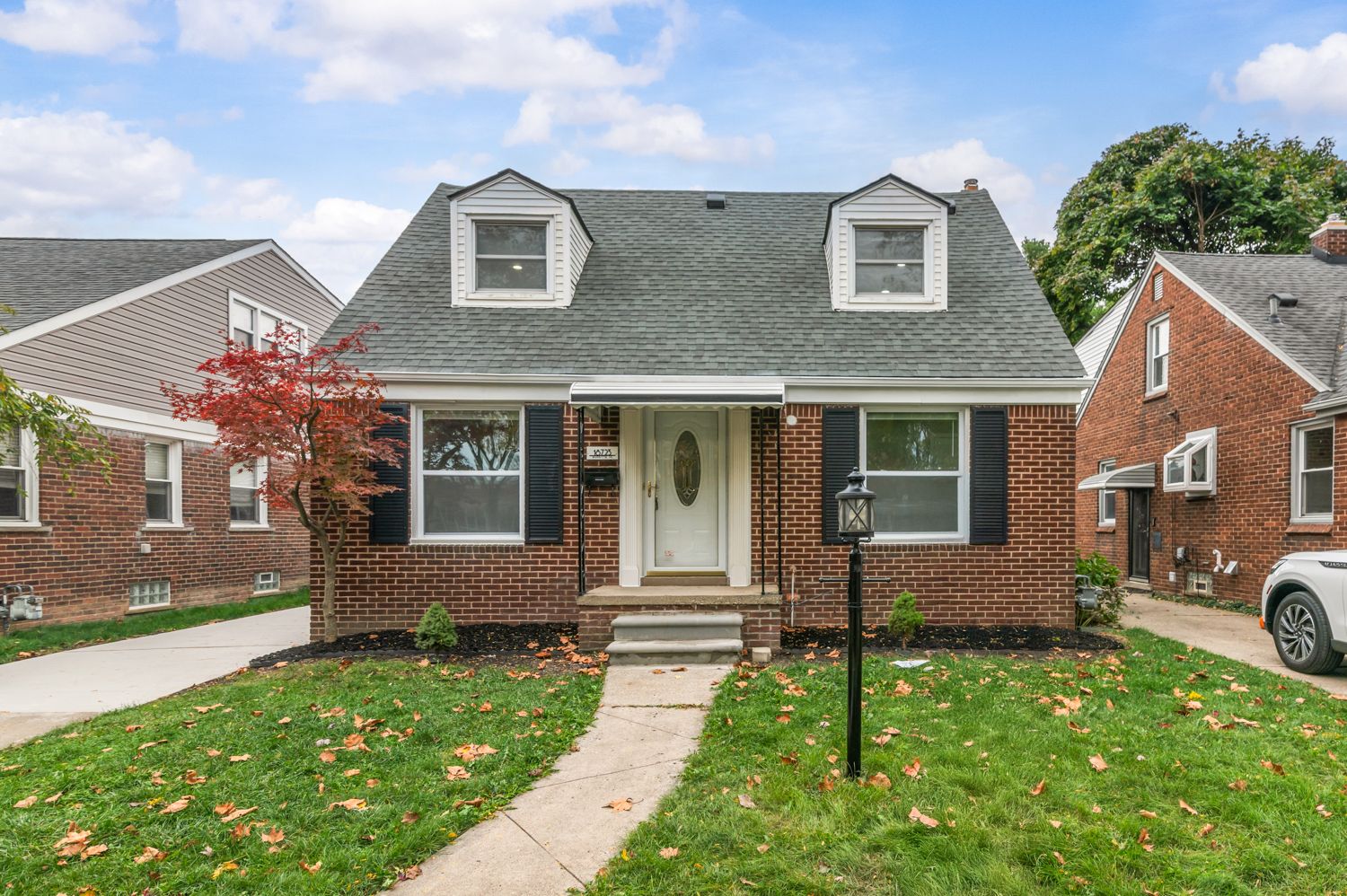 Two-story home with vinyl siding, covered front porch, attached garage, and well-maintained green lawn.
