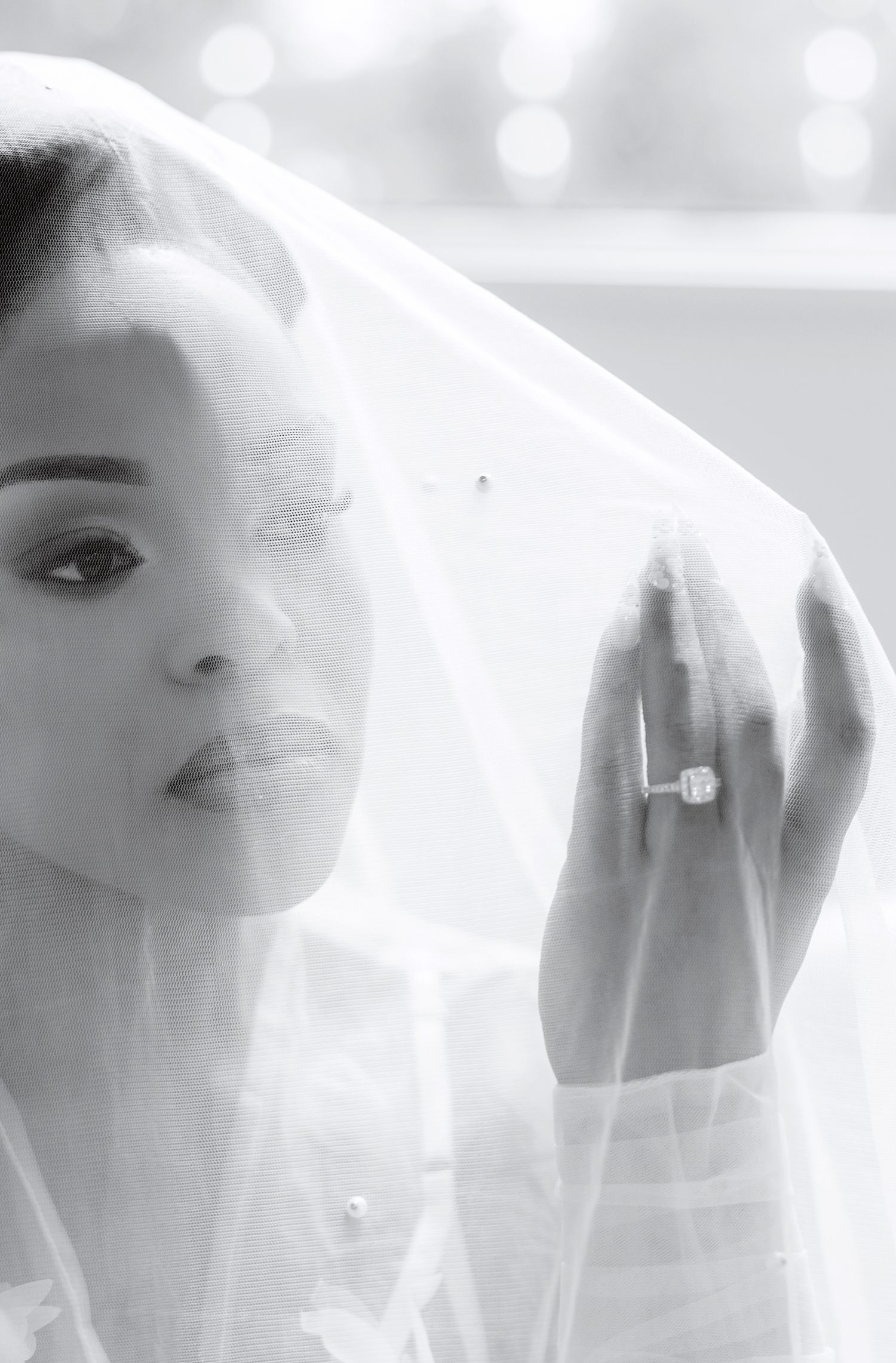 Close-up black and white bridal portrait with veil and diamond engagement ring.