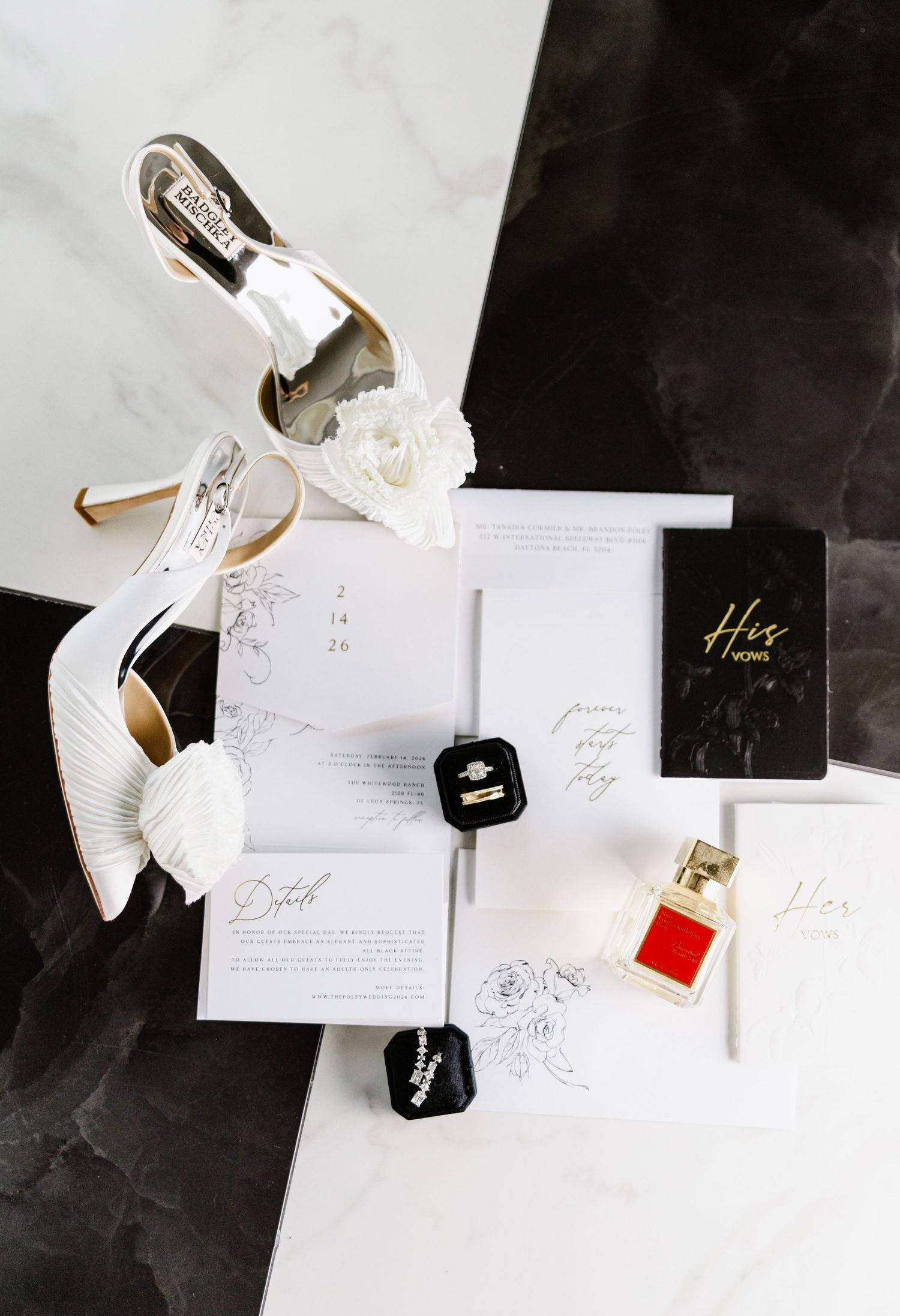 Wedding flat lay featuring white Badgley Mischka heels, ring box, invitations, and His Vows book.