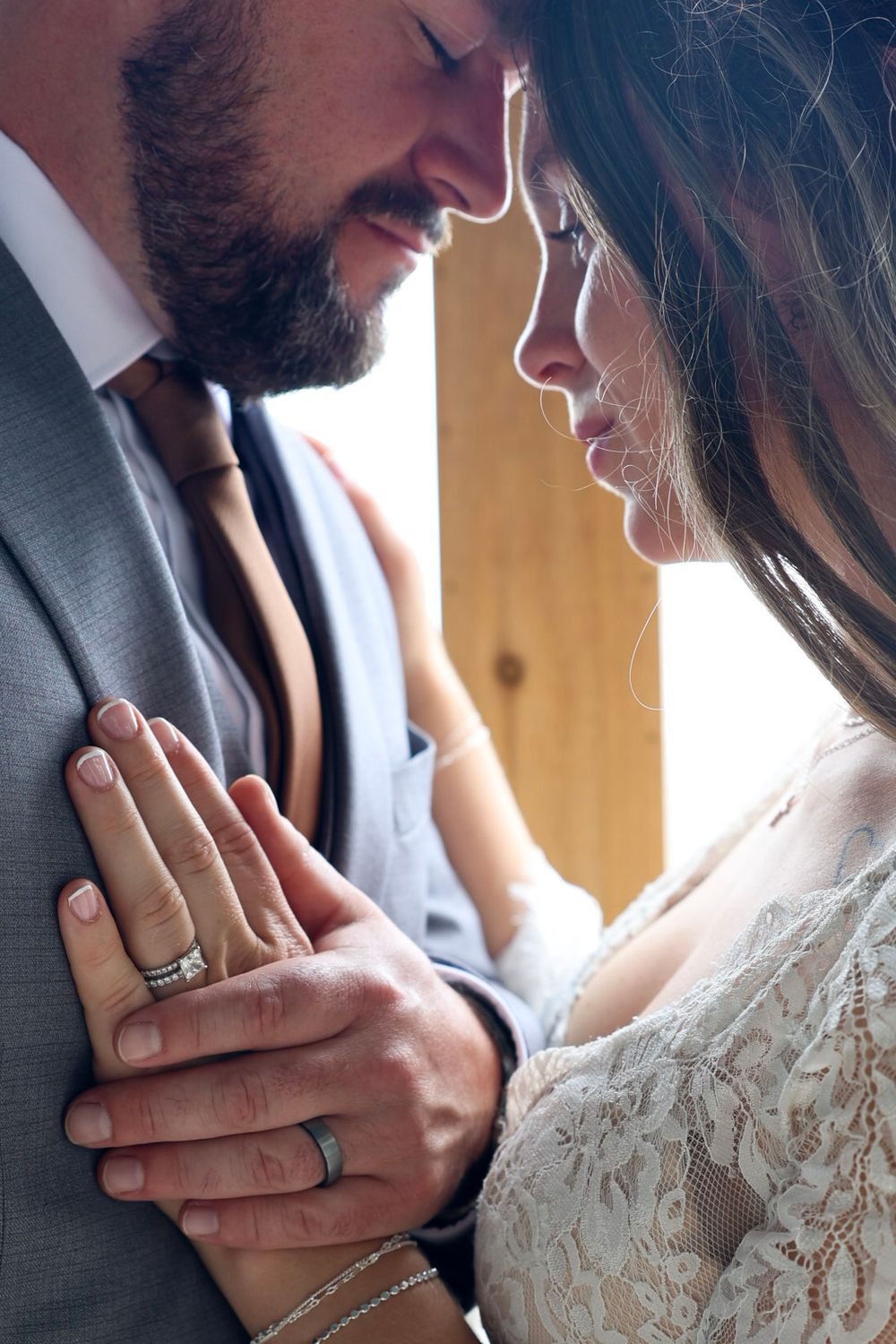 A close-up of a bride and groom sharing an intimate moment, showcasing their wedding rings at the ceremony.