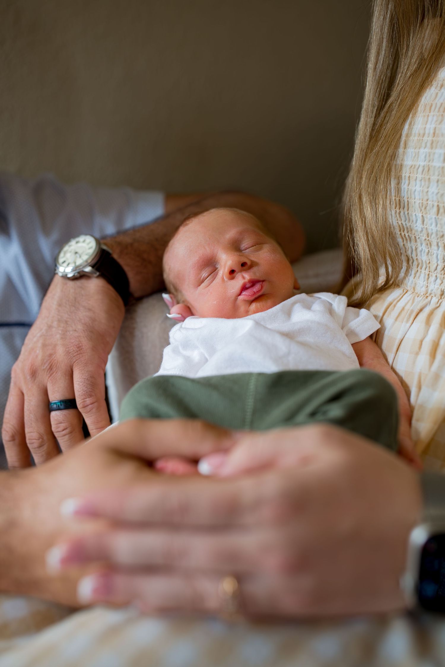 Newborn baby sleeping peacefully while cradled in parents hands shortly after birth.