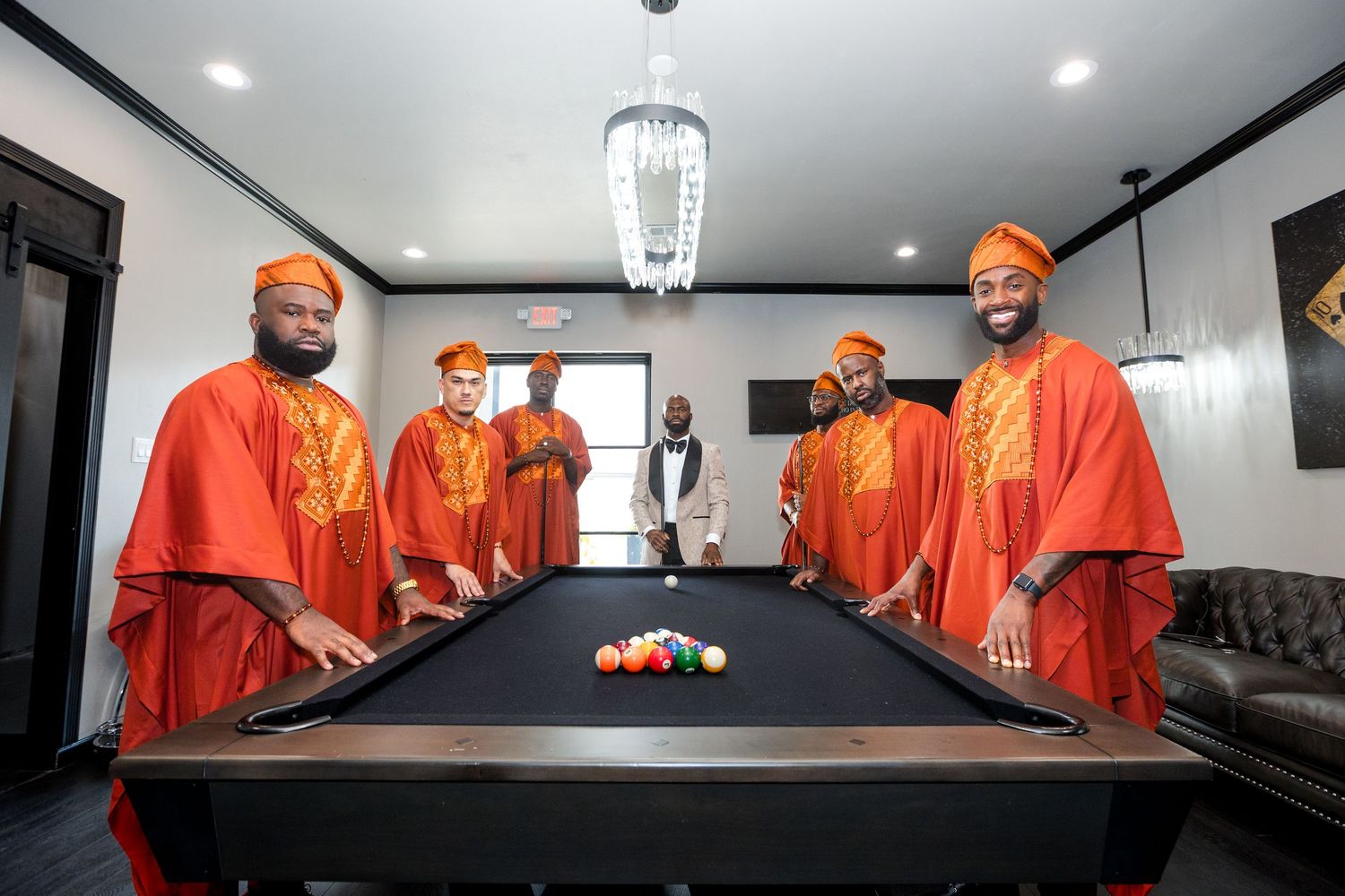 Several individuals in orange uniforms seated at a long dark table under pendant lights.
