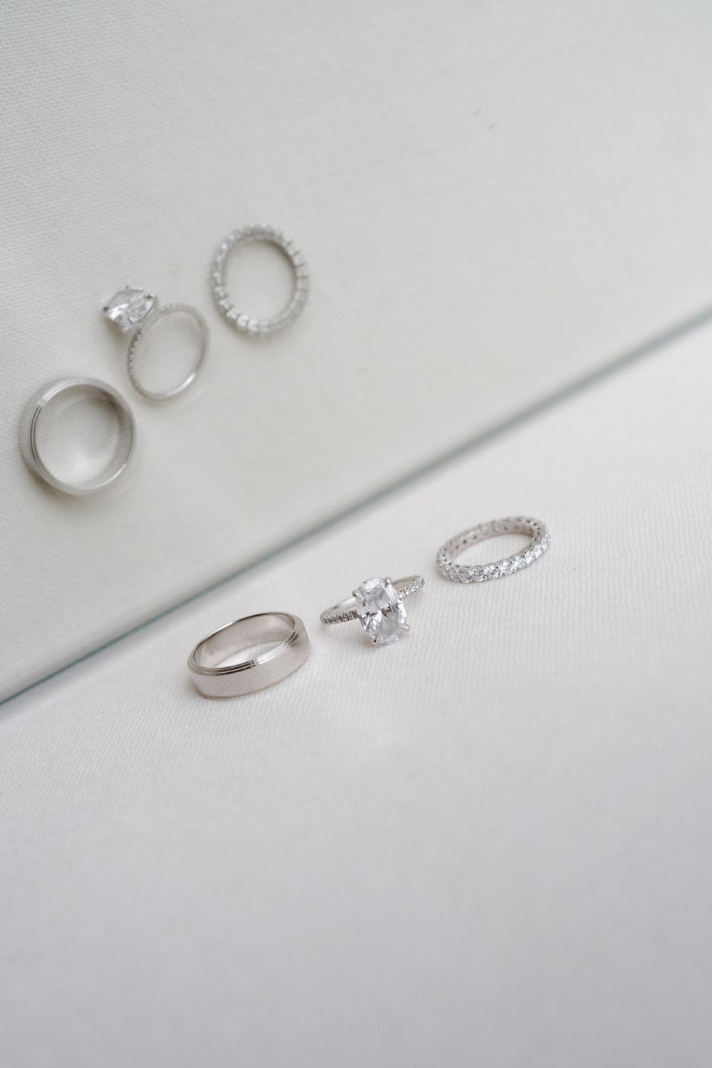 Silver wedding ring set with diamond engagement ring and eternity band displayed on white surface.