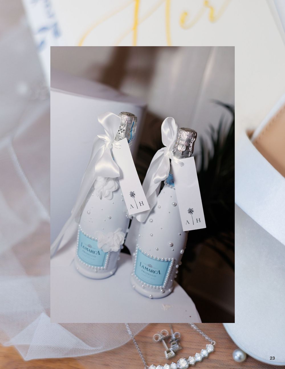 Two decorated champagne bottles with white fabric, blue labels, and ribbon bows, displayed as elegant wedding gifts.