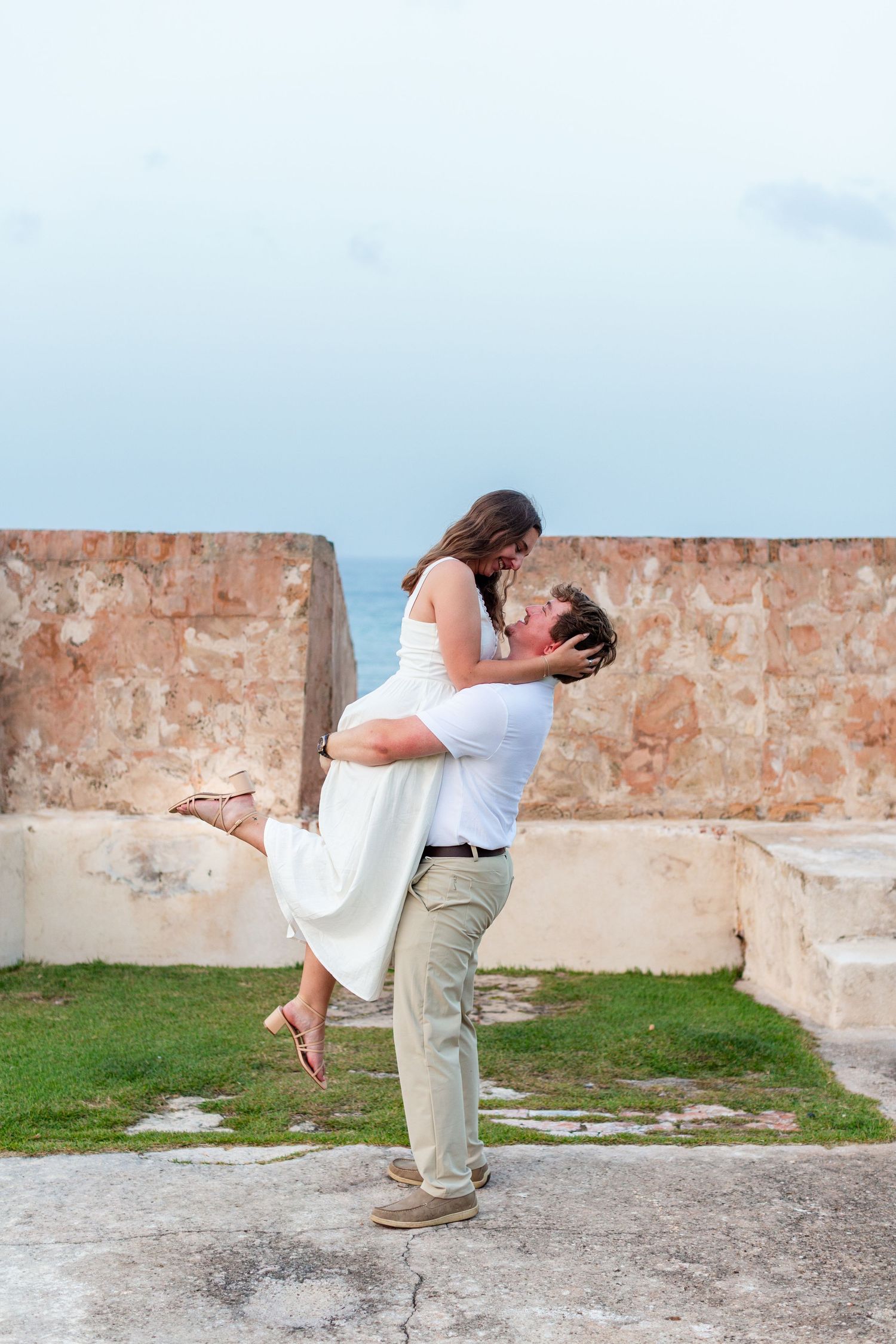 Man lifting a woman for a couples portrait. Engagement photo session in Old San Juan, Puerto Rico.