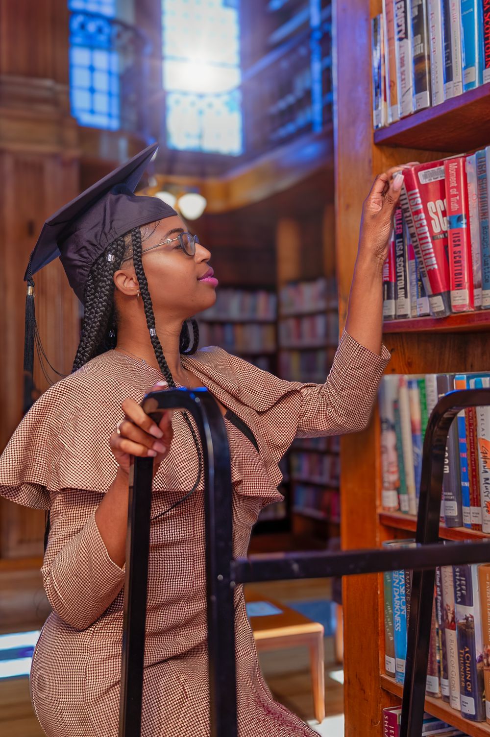 Student browsing books in a traditional wood-paneled library wearing a beige ruffled outfit.