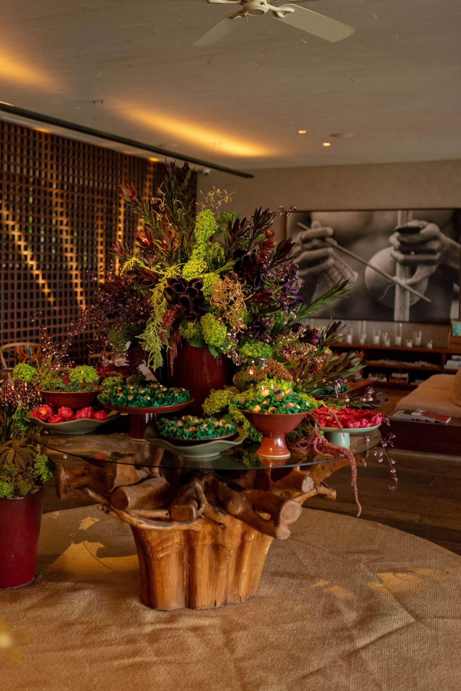 Elegant restaurant centerpiece with lush floral arrangement, colorful dishes, and a rustic wooden table in a warmly lit dining room.