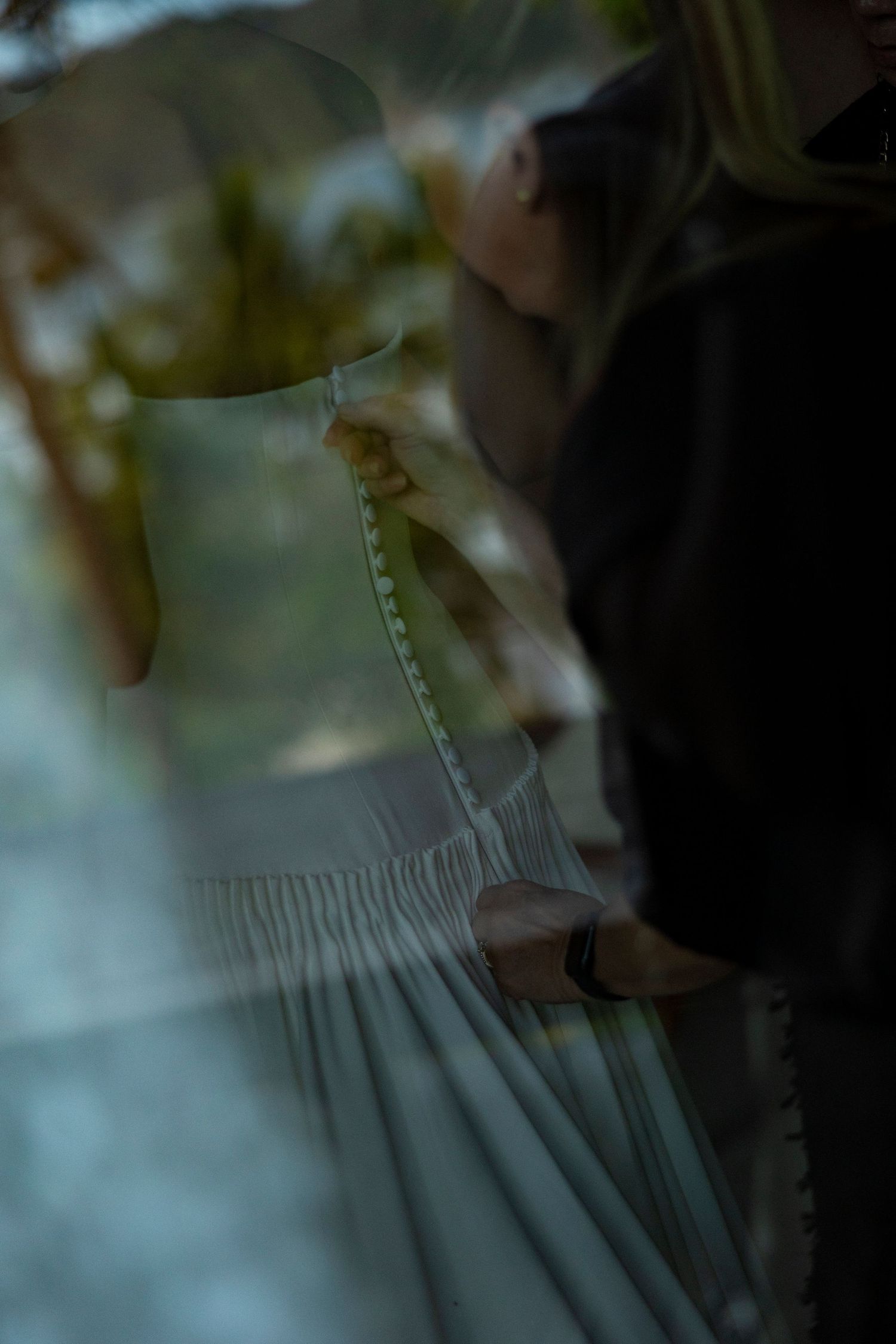 Close-up of a bride being fitted in a white wedding dress with delicate pleating details.