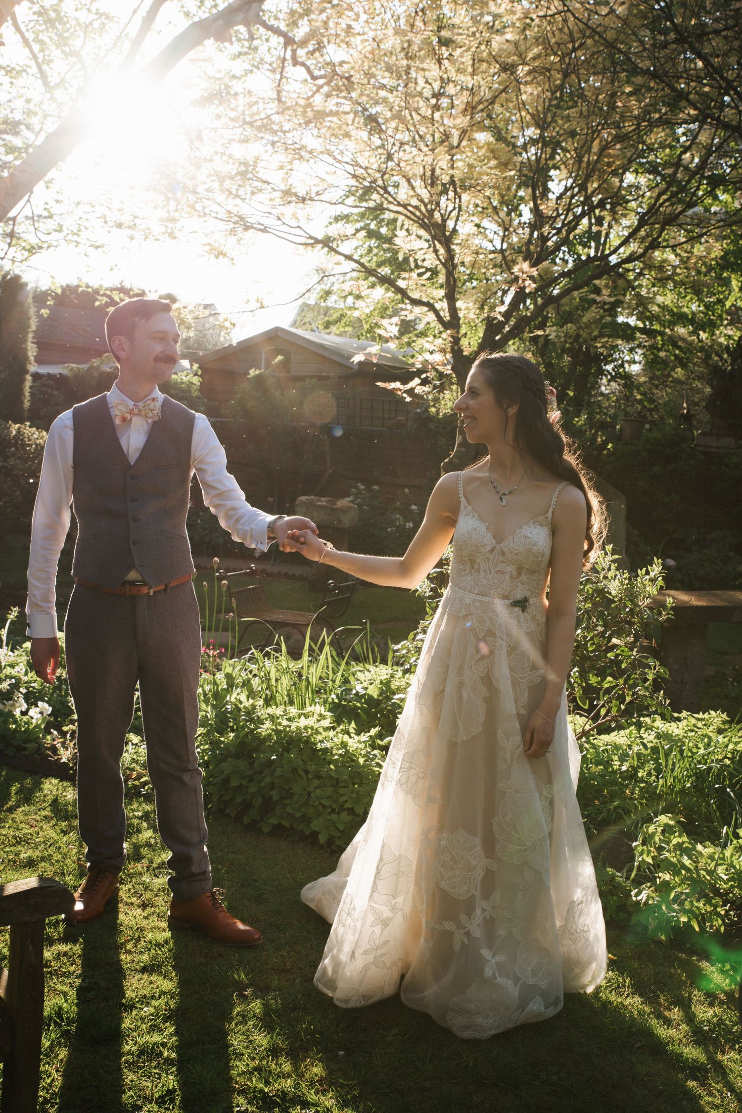 Two people in medieval costumes raise their swords together in a wooded outdoor setting at sunset.