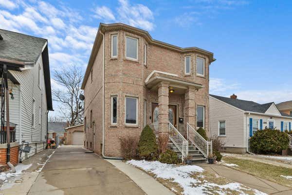 Modern brick two-story home with bay windows, attached garage, and snow-covered front yard.