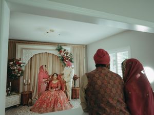 Indian bride seated at altar as family members in traditional attire look on at Sikh wedding.