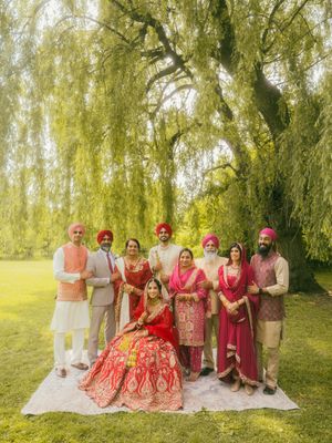 Sikh wedding family portrait under weeping willow tree with bride in red bridal lehenga.