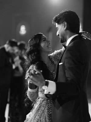 Black and white photo of a couple sharing a joyful first dance at their wedding reception.