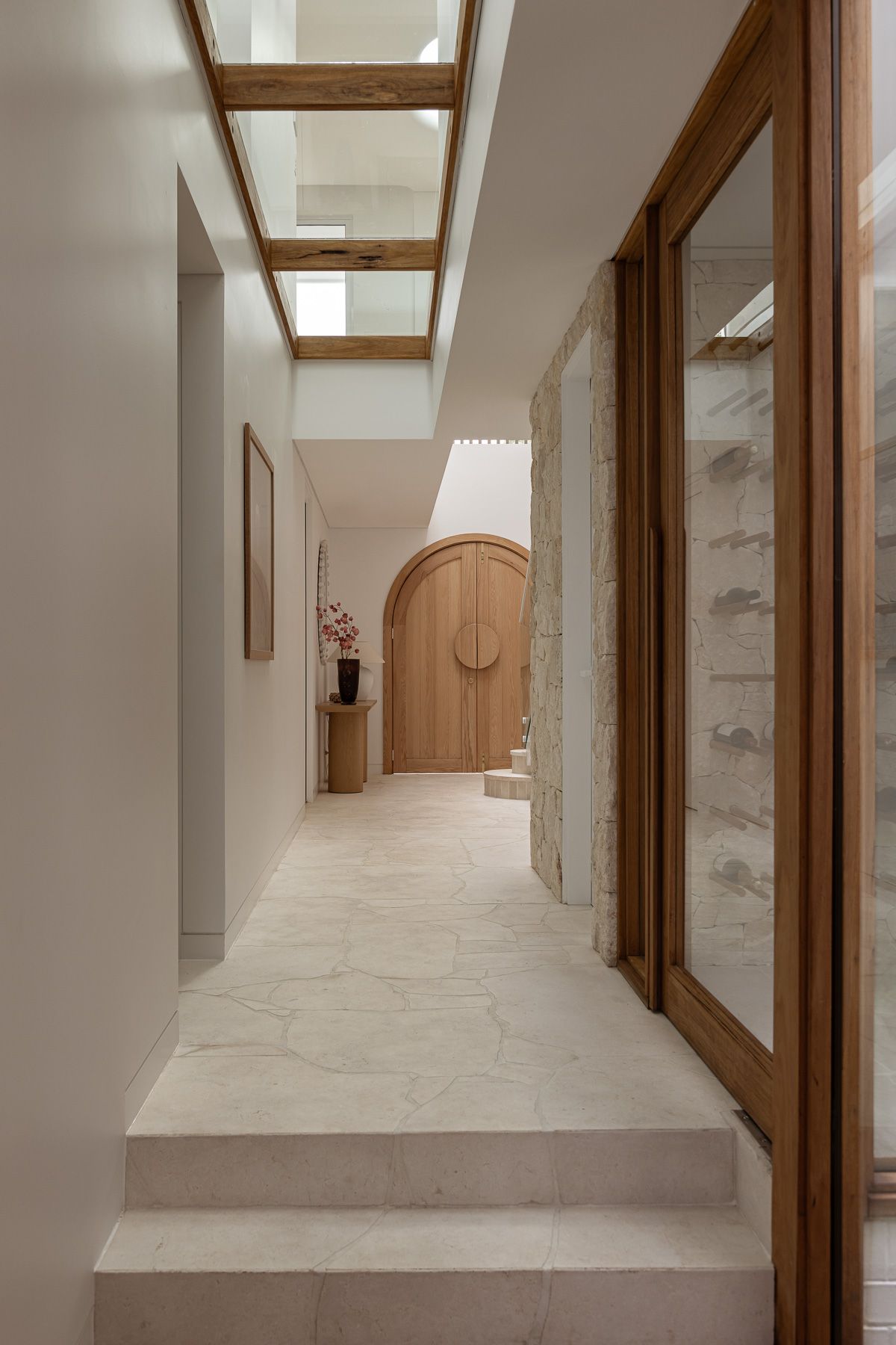 Architectural interior photography capturing skylit hallway and curved timber entry door in Miranda, Sutherland Shire.