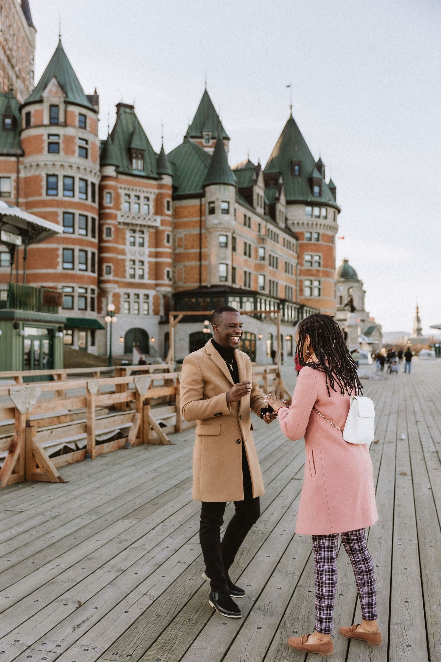 Two people chat on a boardwalk in front of the iconic Chateau Frontenac in Quebec City.