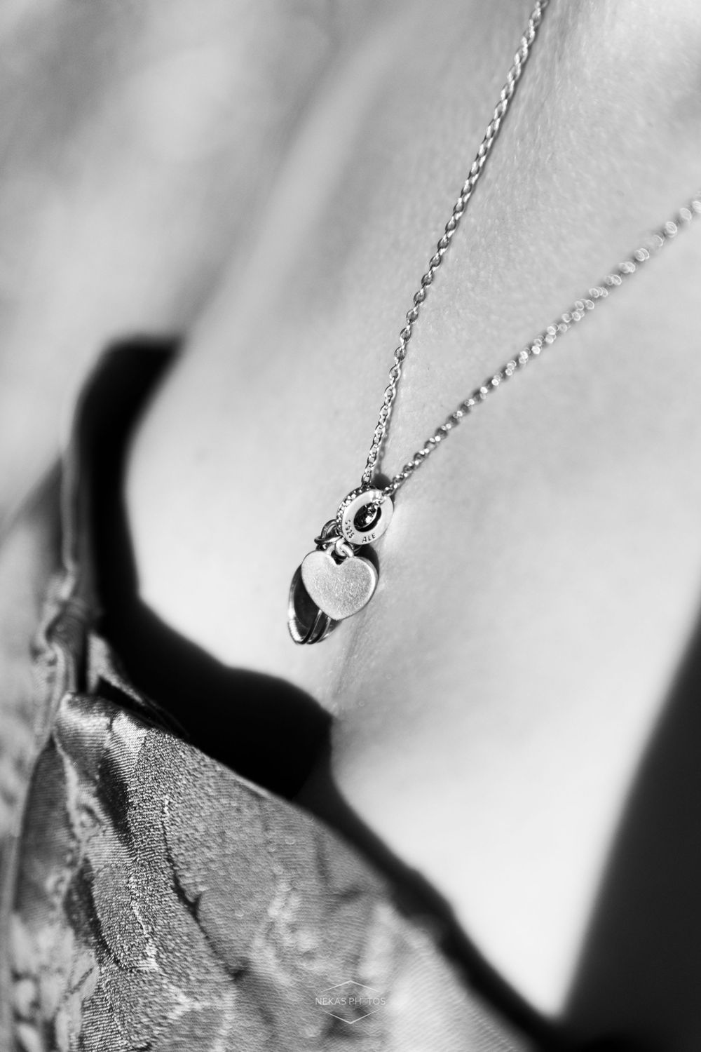 Black and white close-up of a silver owl pendant necklace worn on a womans chest.