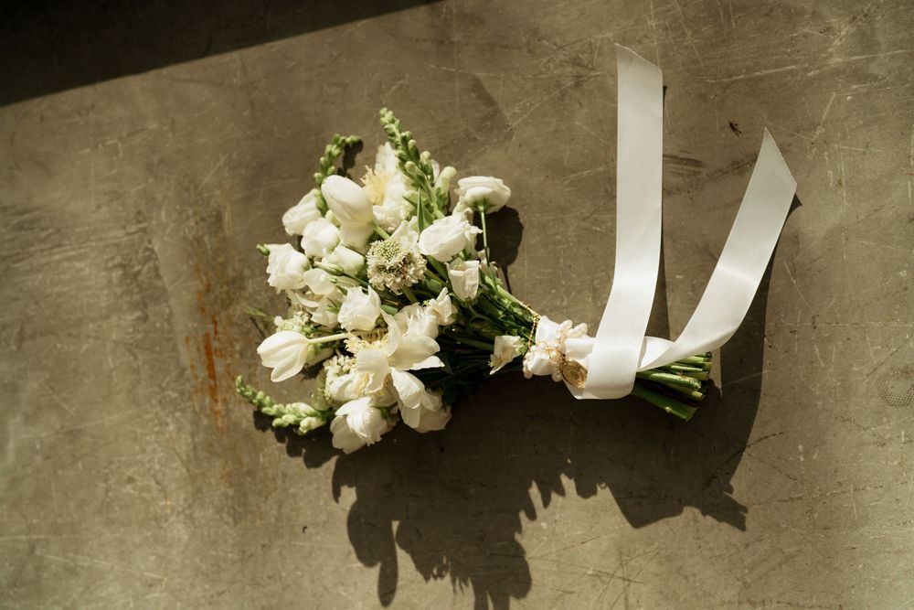 White bridal bouquet with roses and ribbon on concrete surface, perfect for wedding decor inspiration.