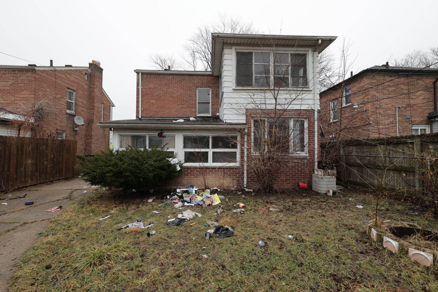 Classic white clapboard bungalow with covered front porch, brick accent wall, and detached garage on a corner lot.
