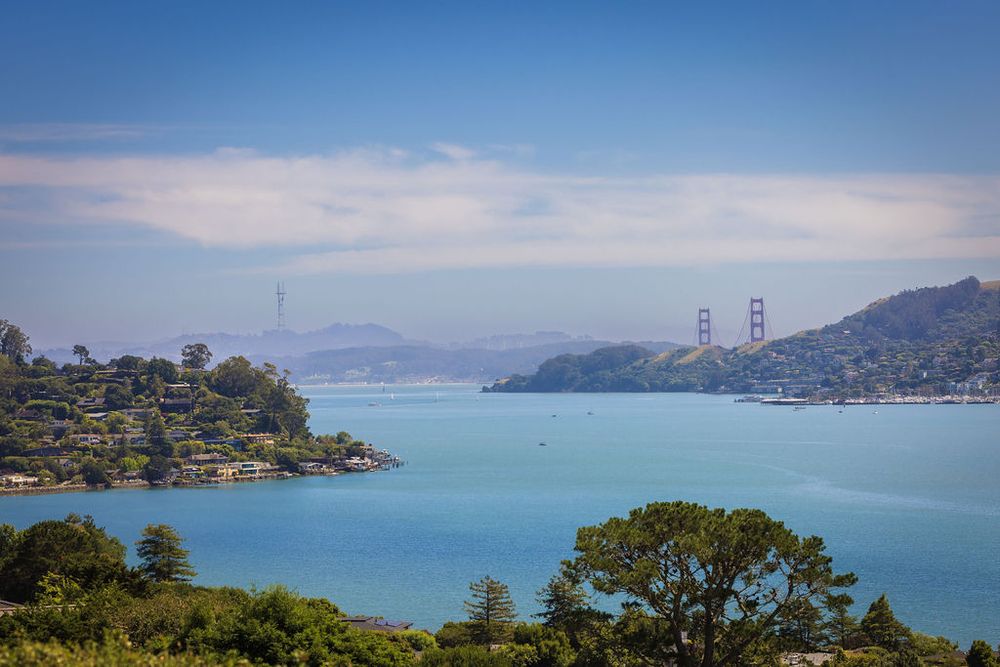 Stunning aerial view of San Francisco Bay with turquoise waters and Golden Gate Bridge in the distance.