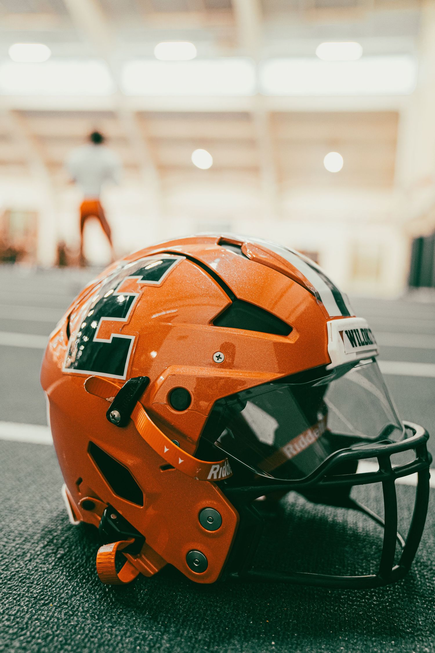 Orange football helmet with protective face mask on display.