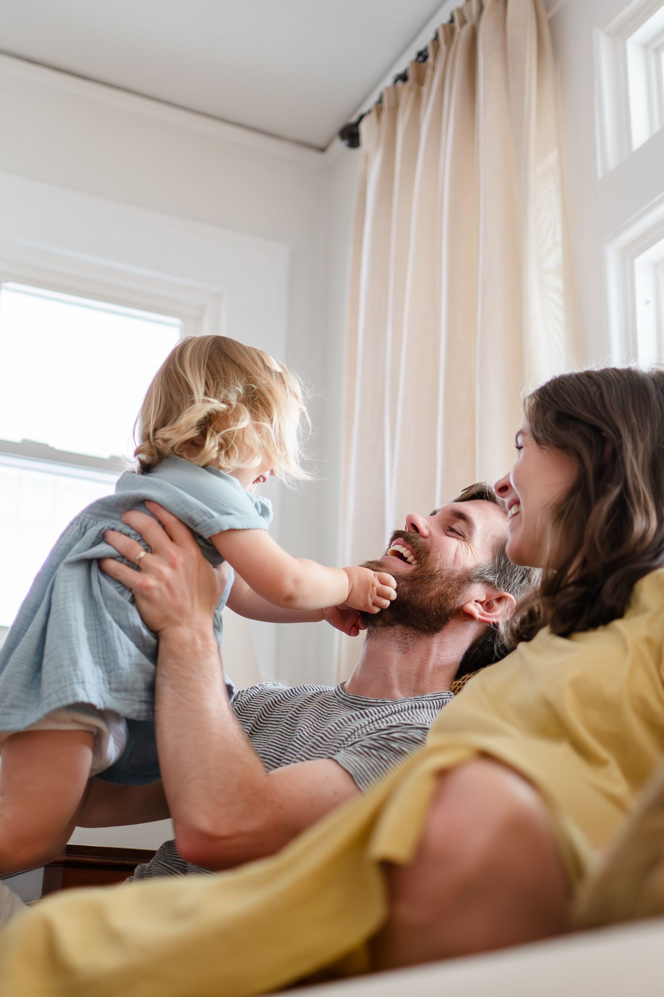 Dad lifts little girl in the air, creating giggle around during a family mini session.