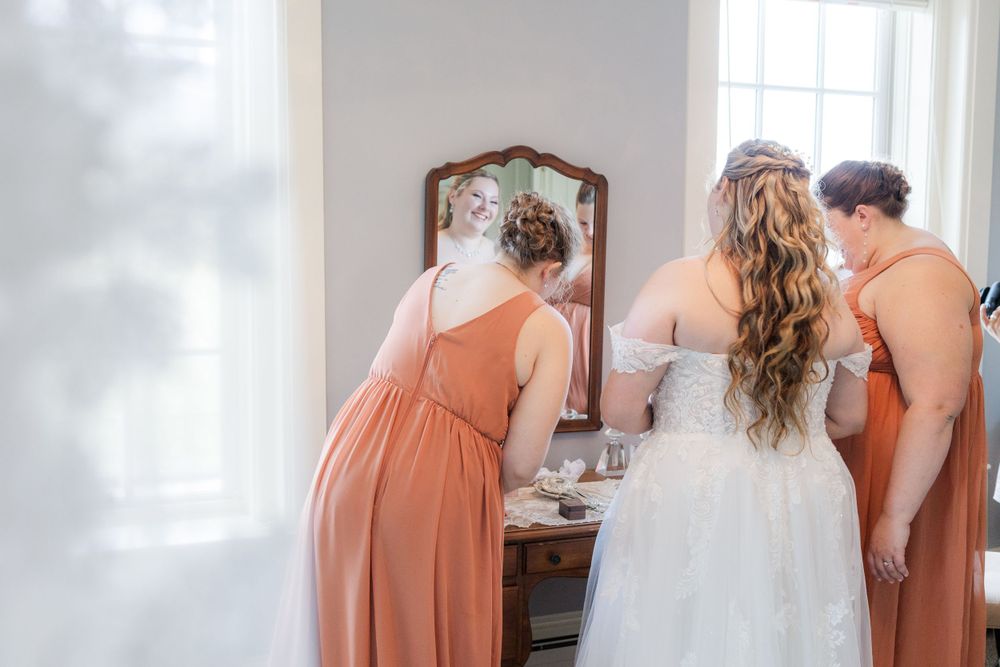 Getting ready scene with coral bridesmaid dresses and white wedding gown.