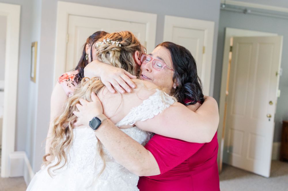 Emotional embrace between two figures in red and white dresses during wedding preparations.