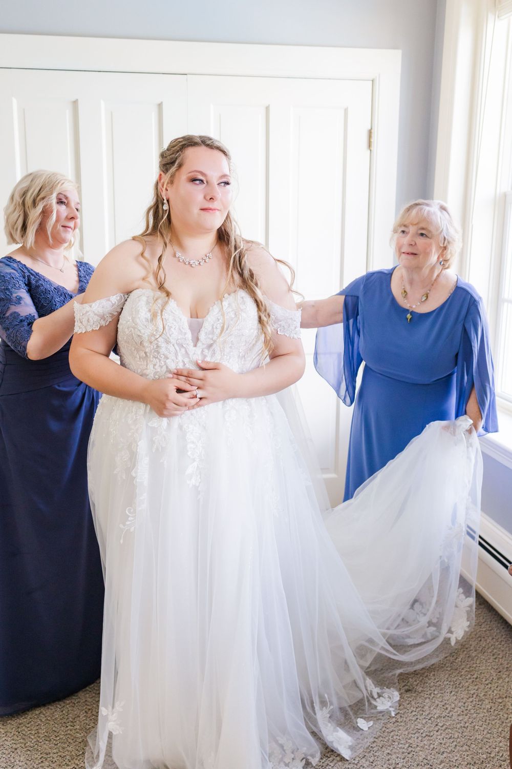 Wedding party helps adjust the bride's beautiful white tulle gown before the ceremony.