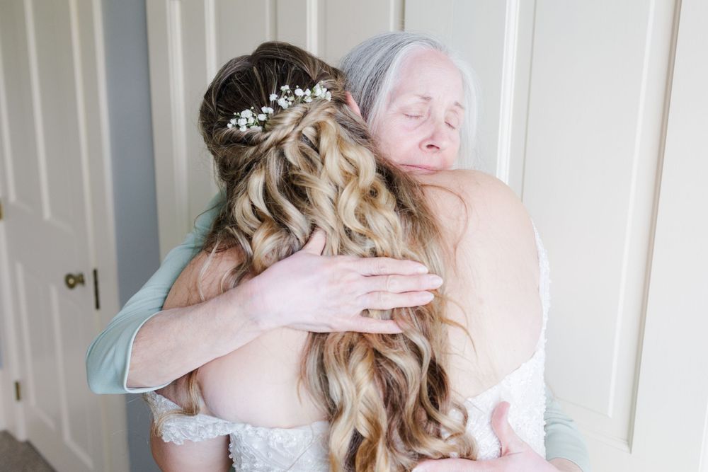 Tender emotional moment shared during wedding preparations in soft natural lighting.