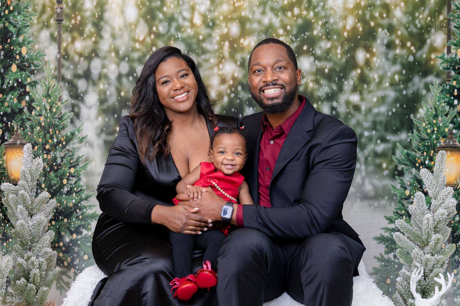 Family of three poses for holiday portraits with festive winter decorations.