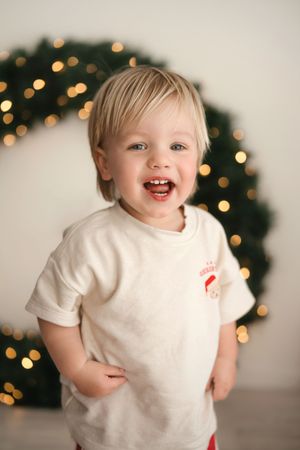 Joyful expression with Christmas tree lights glowing in background during holiday photo session.