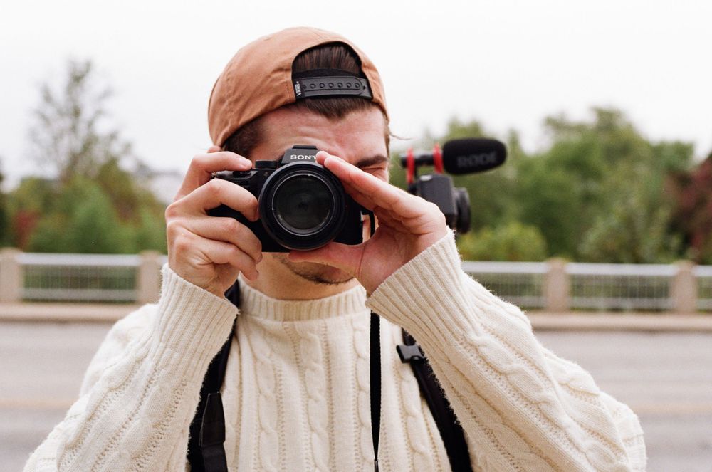 Photographer in white sweater taking picture with camera outdoors near downtown Austin, TX.