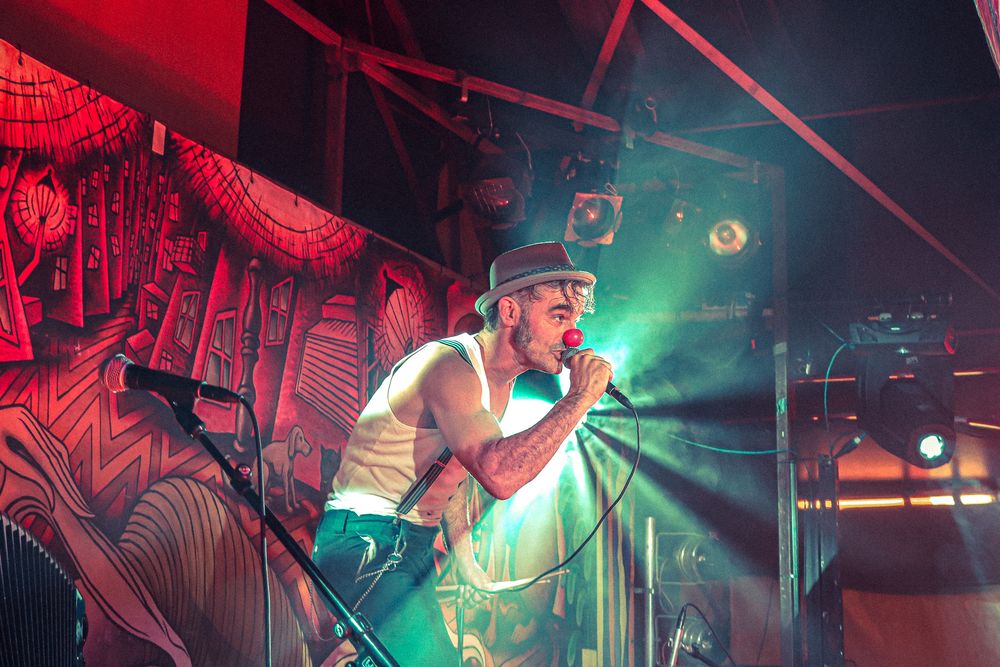 Concert stage bathed in dramatic red and green lighting during a live music performance.